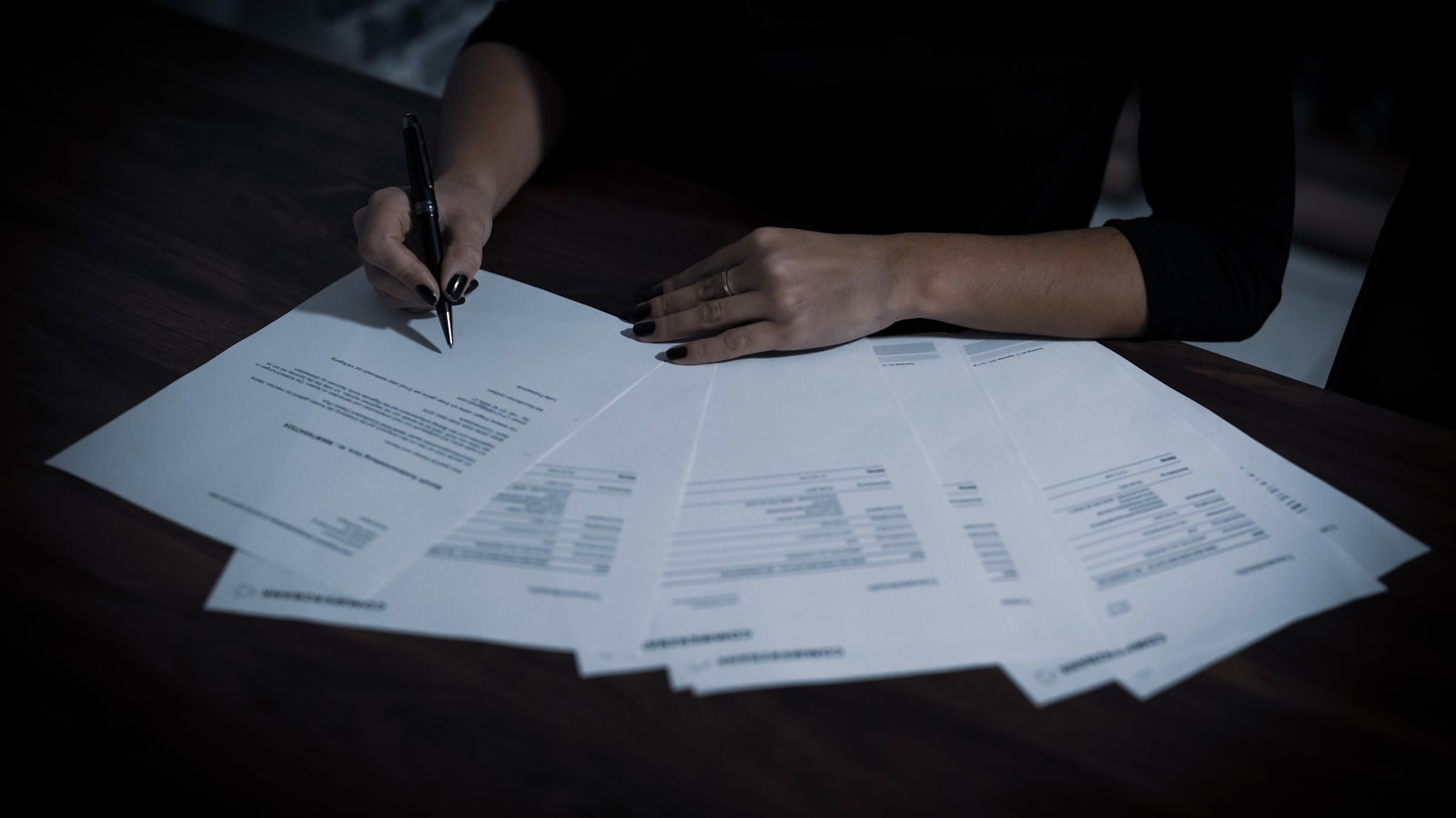 Personne examinant des relevés et des factures étalés sur une table