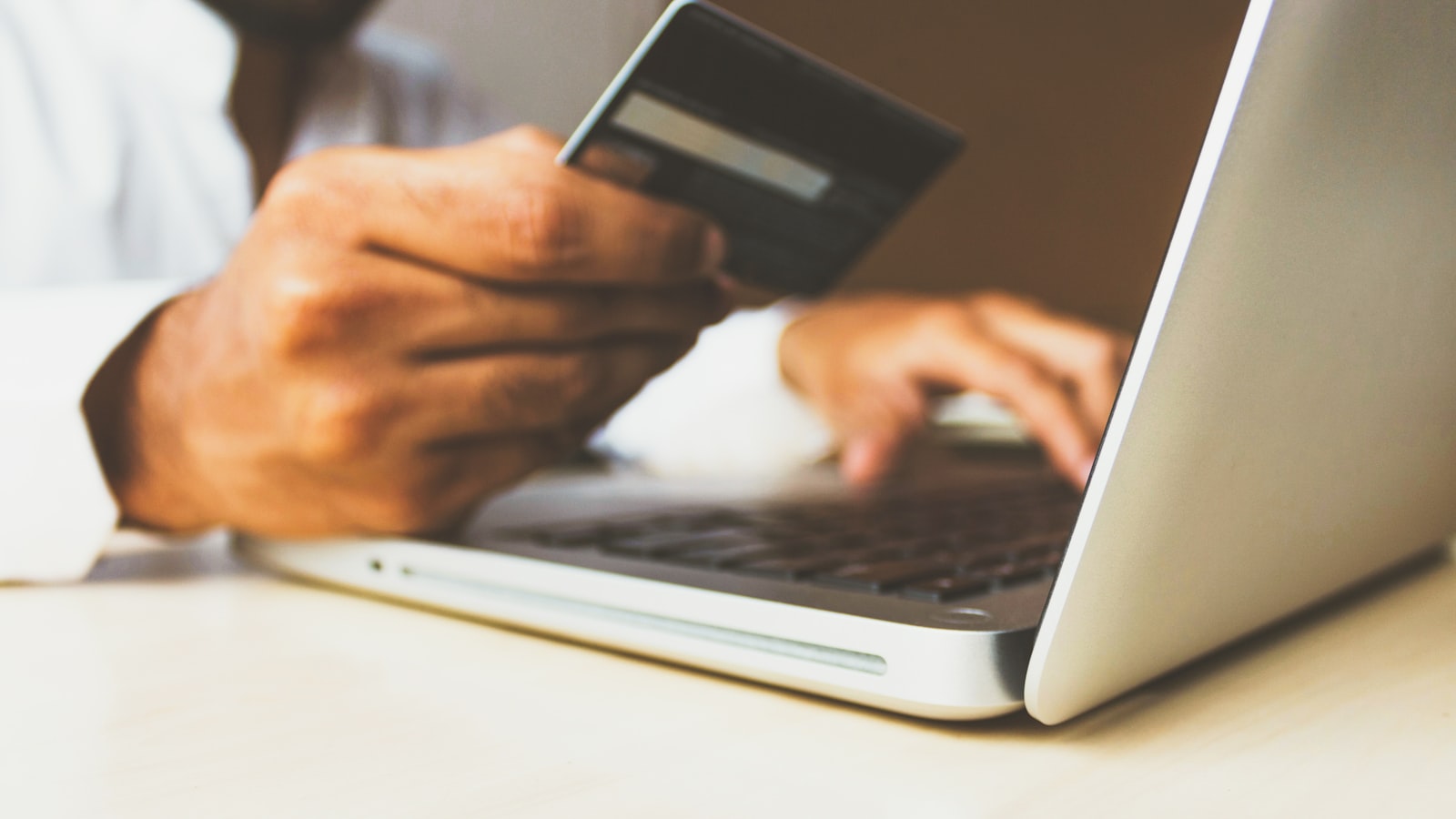 Personne tenant une carte bancaire devant un ordinateur portable, illustration d’un virement en ligne