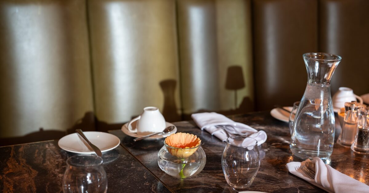Carafe d’eau et verres servis sur une table de restaurant en terrasse
