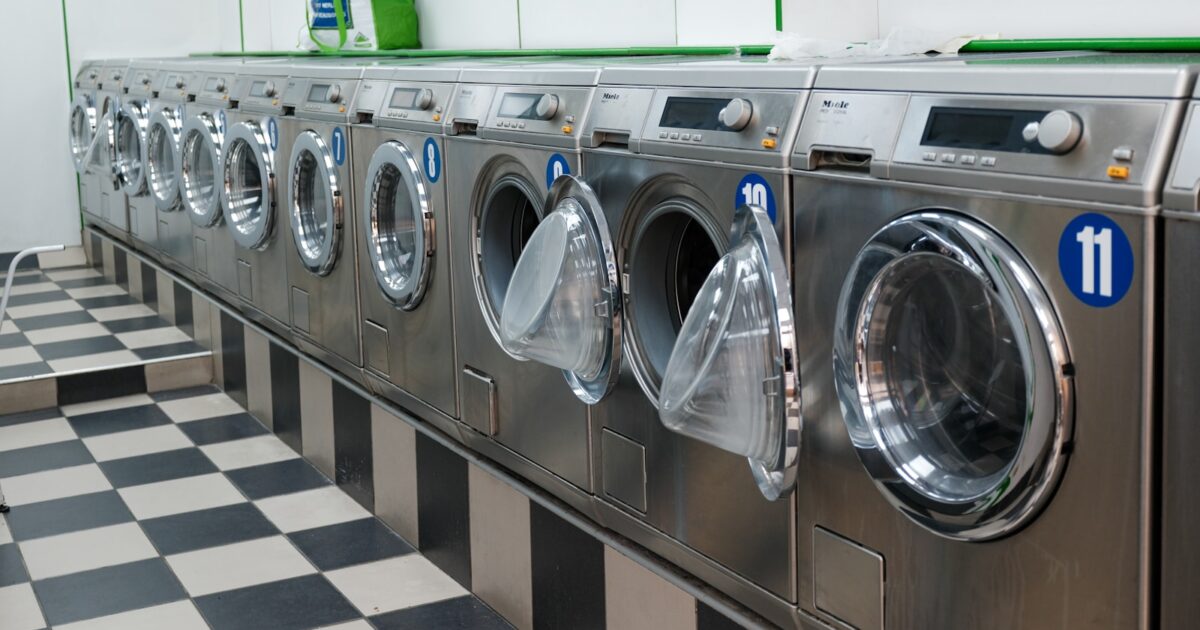 Client comparant les étiquettes de deux lave-linge dans un magasin d'électroménager